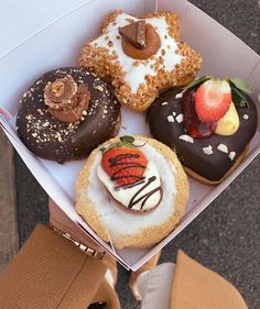 a box filled with assorted donuts covered in frosting and fruit toppings