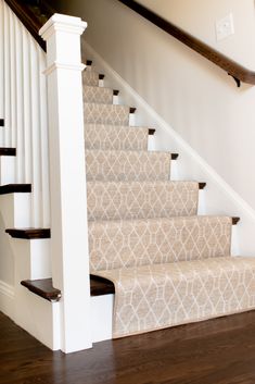 a staircase with carpeted steps and white banisters on the bottom floor in a home