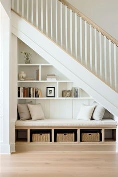 a white staircase with bookshelves and baskets under the stairs