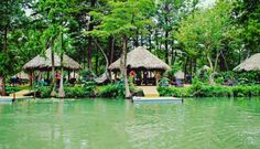 the water is green and clear with some huts on each side, surrounded by trees