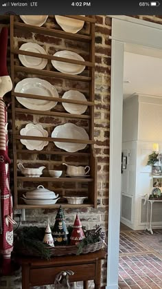 a room filled with lots of white plates on top of a wooden shelf next to a brick wall