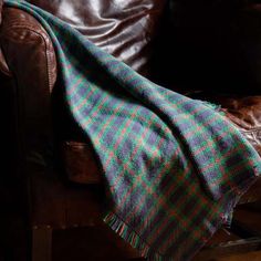 a brown leather chair with a plaid blanket on it