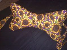 a yellow and purple flowered dog pillow on a black surface with a white background