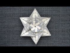 an origami star with dollar bills in the center on a gray background that appears to be made out of paper