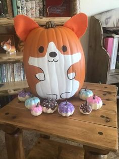 a pumpkin shaped like a corgi sitting on top of a table with candy