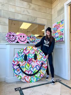 a woman standing next to a large smiley face sign