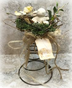 a stuffed animal sitting on top of a wooden stand with grass and flowers in it