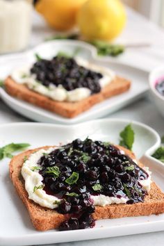 two pieces of bread with blueberry sauce and whipped cream on them sitting on plates