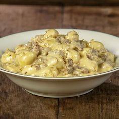 a white bowl filled with macaroni and cheese on top of a wooden table