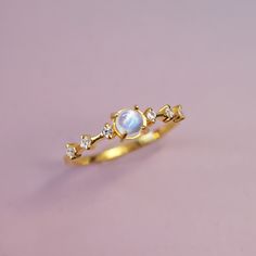 Introducing Moonlight – a delicate and enchanting ring crafted from 14k solid gold, featuring a mesmerizing moonstone as its centerpiece, with sparkling white topaz accents. The moonstone’s ethereal glow shimmers with soft hues of blue and white, reminiscent of moonbeams dancing across a calm night sky. The brilliant white topaz stones are tiny stars, adding just the right touch of elegance and radiance. Perfect for both everyday wear and special occasions, Moonlight embodies a timeless blend of Celestial White Moonstone Ring, Ethereal Gold Moonstone Ring For Gift, Celestial 14k Gold Moonstone Ring For Gift, Celestial Multi-stone Moonstone Ring, Luxury Elegant Moon-shaped Moonstone Ring, Calm Night, Tiny Star, Ring Crafts, Topaz Stone