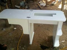 a white desk sitting in the middle of a room next to a chicken coop with chickens around it