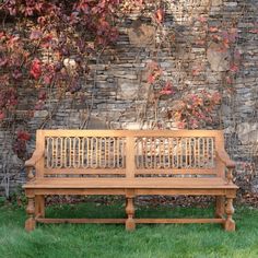 a wooden bench sitting in front of a brick wall with vines growing on it's sides