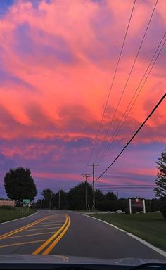 the sun is setting over an empty road with power lines and telephone poles in the foreground