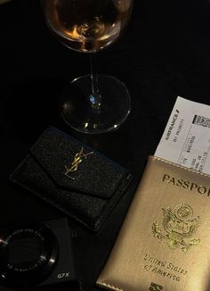 a passport, wine glass and camera on a table