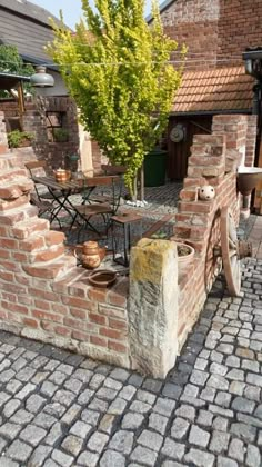 an outdoor table and chairs made out of bricks on a cobblestone patio area