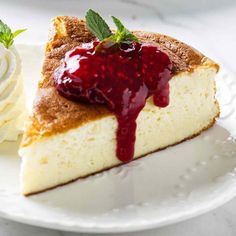 a piece of cheesecake on a plate with whipped cream and raspberry sauce