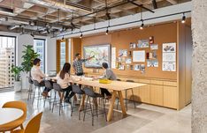 people are sitting at a table in an office with large windows and wooden paneling