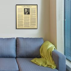 a blue couch with a yellow throw blanket on it in front of a white wall