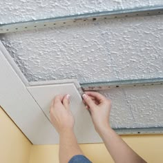 a person working on a ceiling with white paint