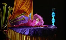 a woman laying on top of a purple bed