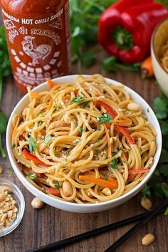 a white bowl filled with noodles and vegetables next to chopsticks on a wooden table