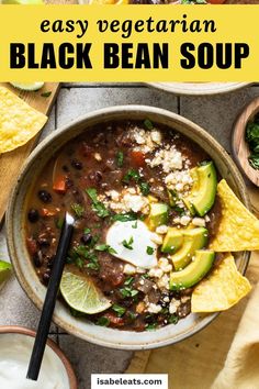 a bowl of black bean soup with tortilla chips and avocado on the side