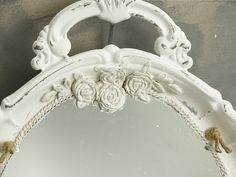 an ornate white mirror with flowers on it