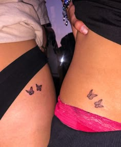 two women's butts with butterflies on their side, both showing small tattoos