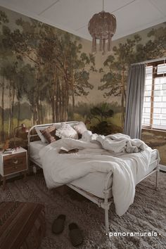 a bed sitting in a bedroom next to a wall with a forest mural on it