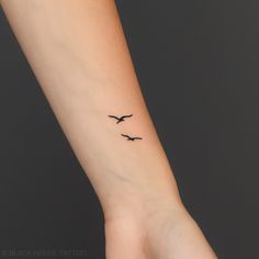 two birds flying in the sky on a woman's left wrist tattoo design by blackhouse tattoo