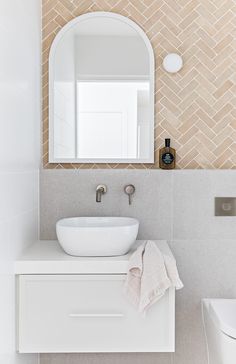 a white sink sitting under a bathroom mirror next to a wall mounted faucet