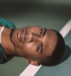 a close up of a person laying on a tennis court with a chain around his neck