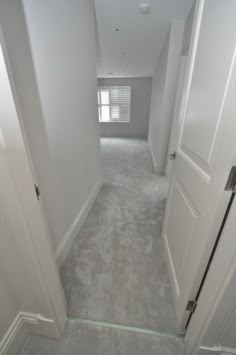 an empty hallway with white walls and carpet