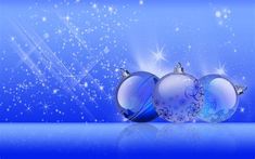 three blue christmas balls with snowflakes and sparkles in the background on a shiny surface