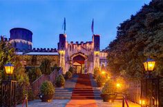 a large castle like building lit up at night with lights on the steps leading to it