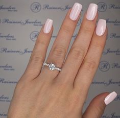 a woman's hand with a pink manicured nail polish and a diamond ring