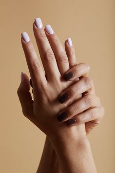 a woman's hands with white and brown nail polish holding her hand up to the camera