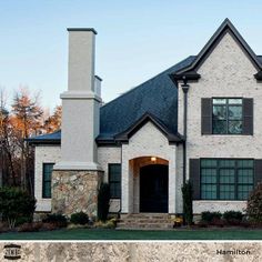 a large white brick house with black shutters and stone steps leading up to the front door