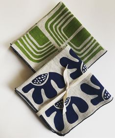 two napkins with blue and green designs on them sitting next to each other in front of a white background