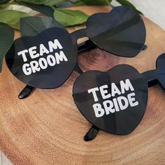 three heart shaped sunglasses with the words team bride and groom on them sitting on top of a piece of wood