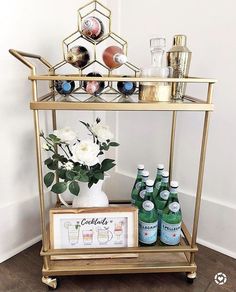 a gold bar cart with bottles and drinks on it, along with an instagram sign