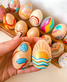 a person is holding some painted eggs in their hand and there are other ones on the table