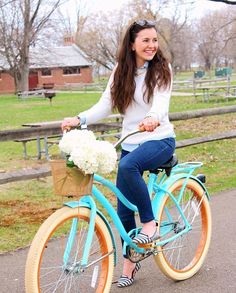 a woman riding a blue bicycle with flowers in the basket