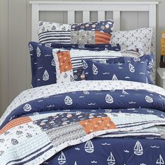 a bed covered in blue and white sheets with sailboats on them