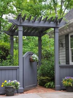 a gray house with a gate and flowers in the front yard