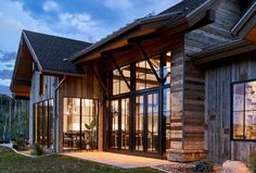 a large wooden building with glass doors and windows on the side of it at dusk