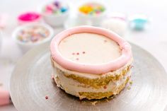 a frosted cake sitting on top of a plate with sprinkles around it