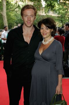 a man and woman standing next to each other on a red carpet