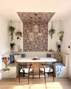 a dining room table with two chairs and a bench in front of a colorful wall