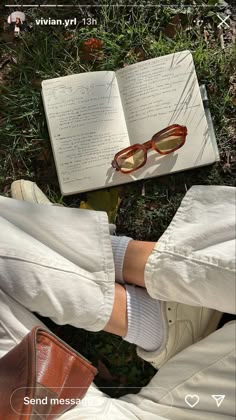 a person wearing white pants and brown shoes with their legs crossed next to an open book